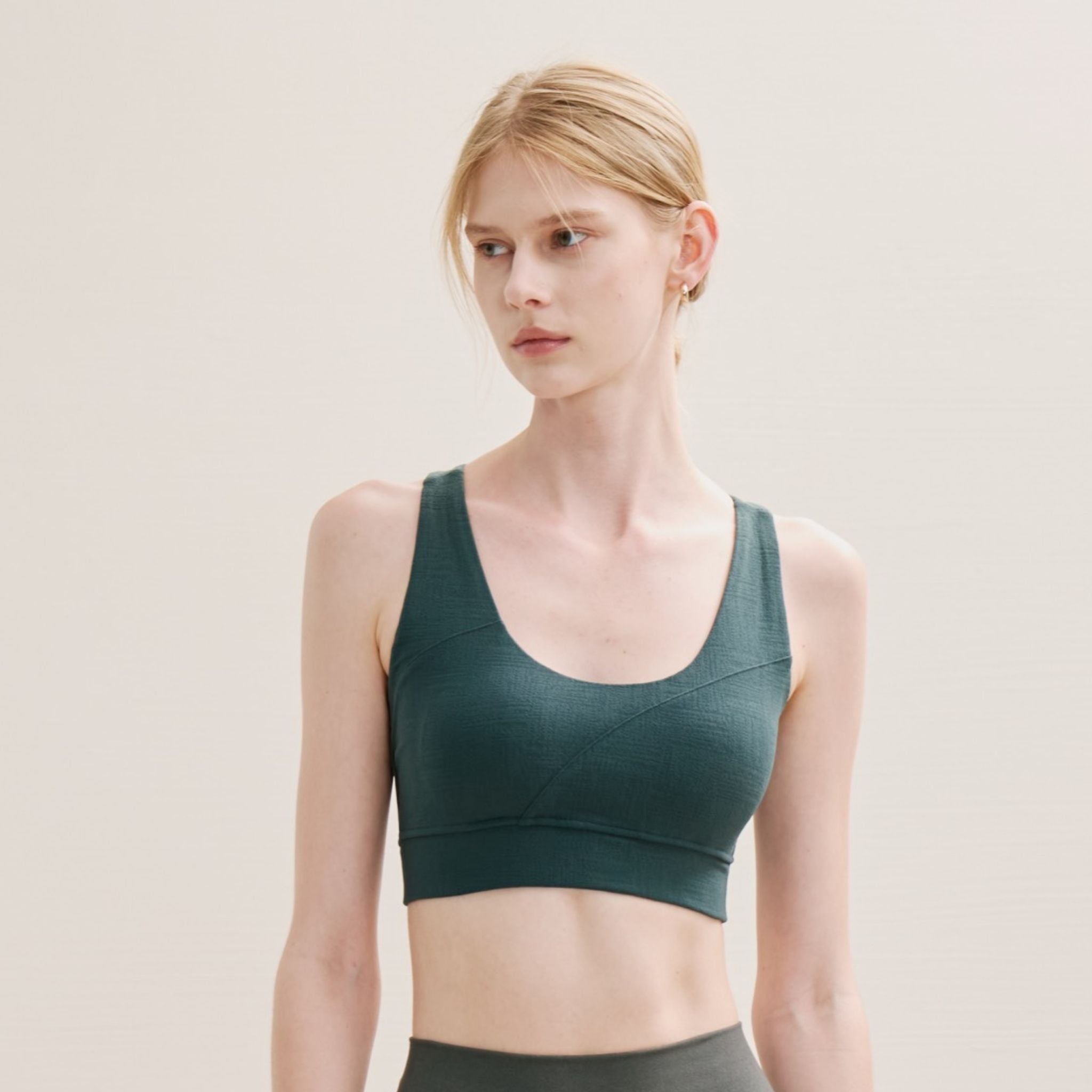 Woman wearing a green sports bra against a plain background