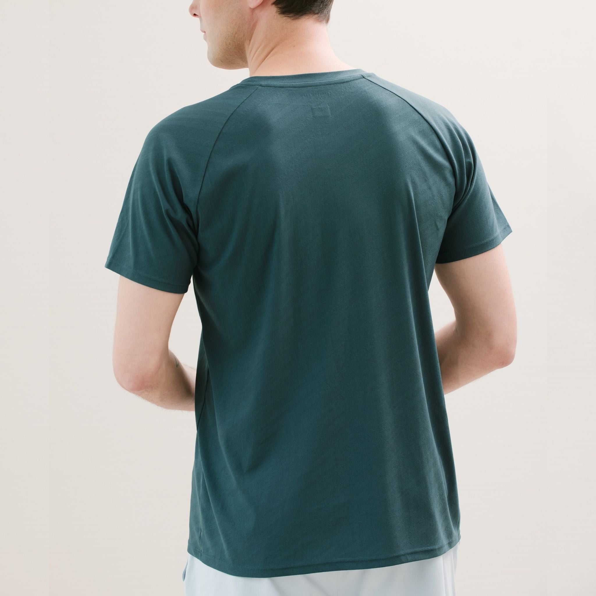 Person wearing a dark green t-shirt against a plain background