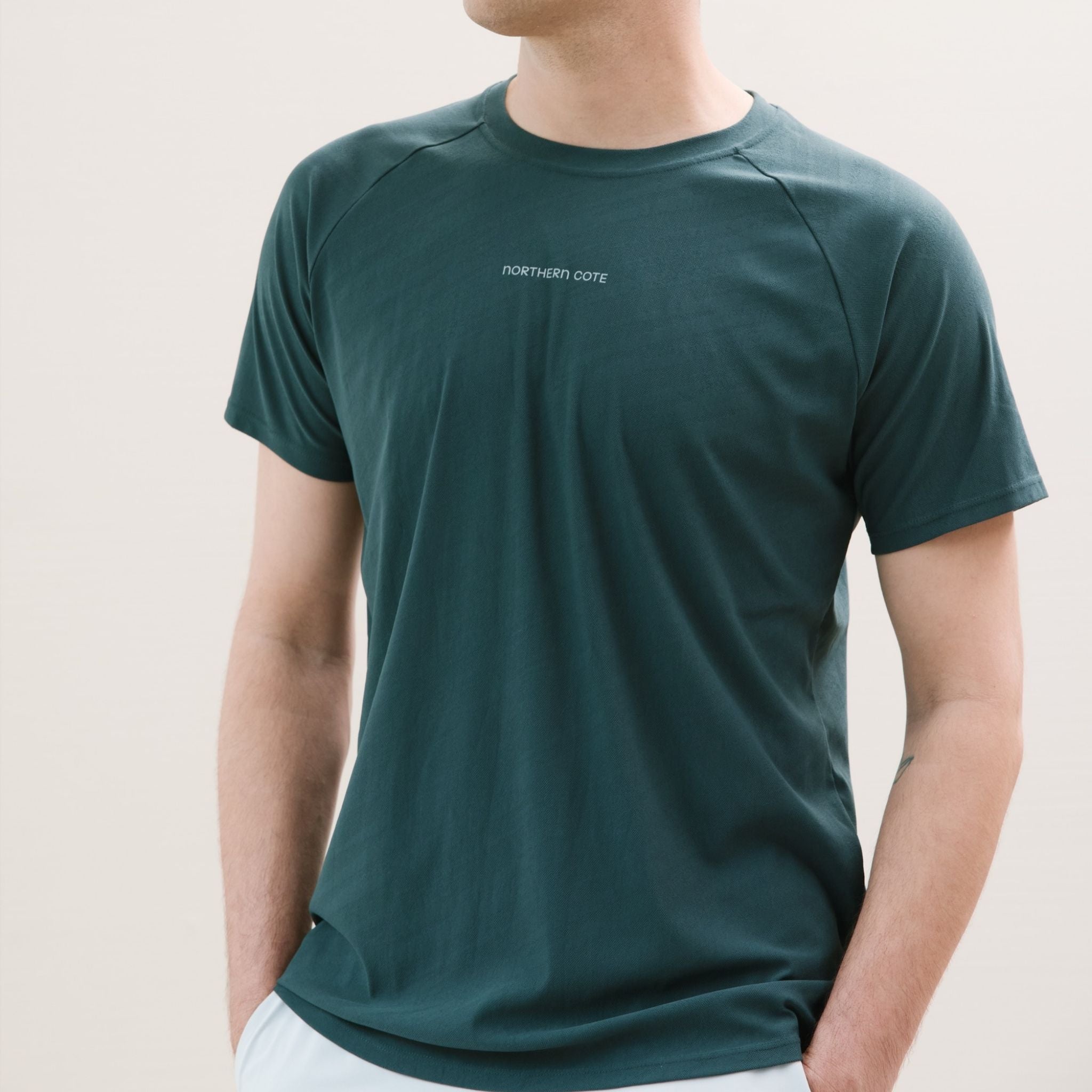 Person wearing a dark green t-shirt on a plain background