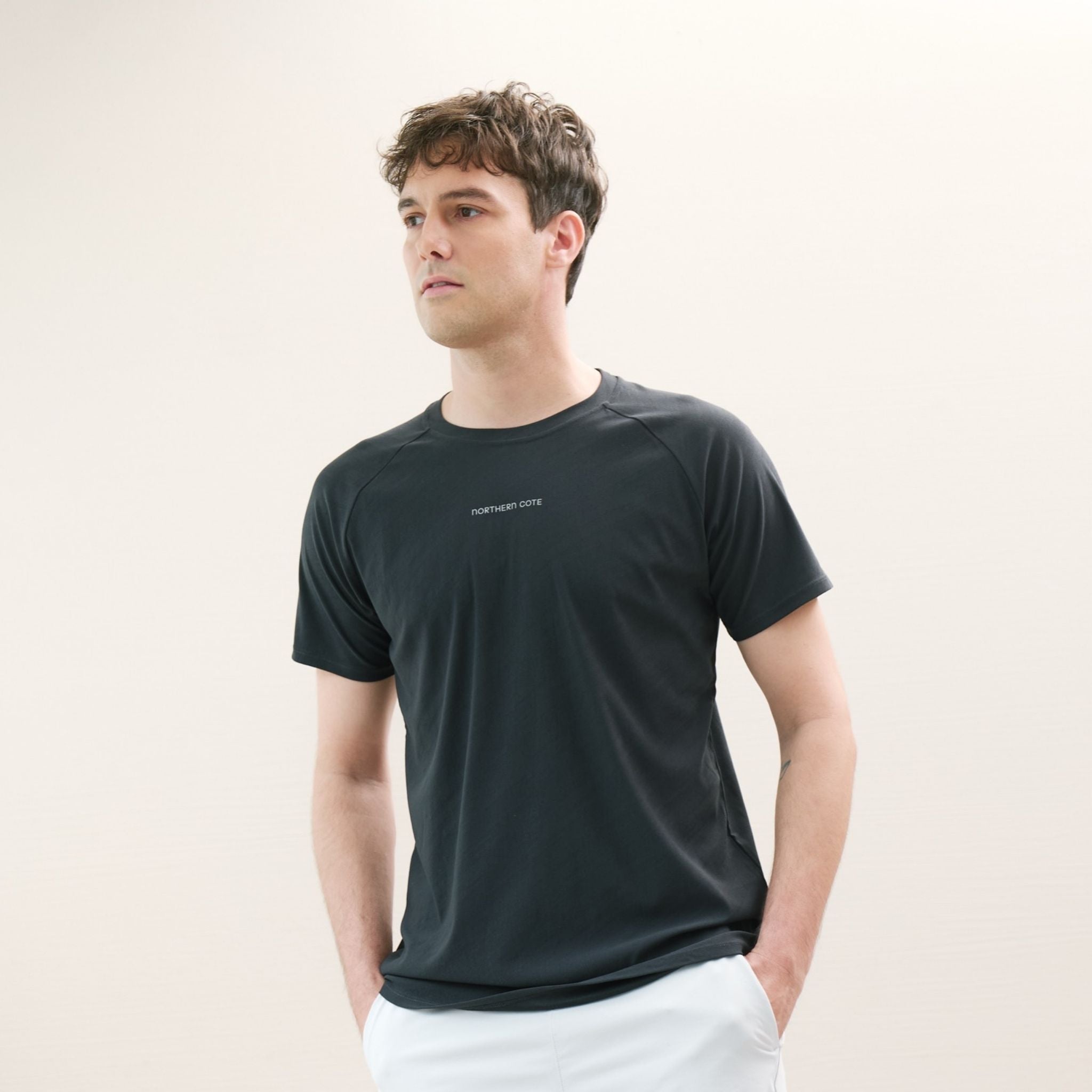 Man wearing a dark green t-shirt with a logo on a white background