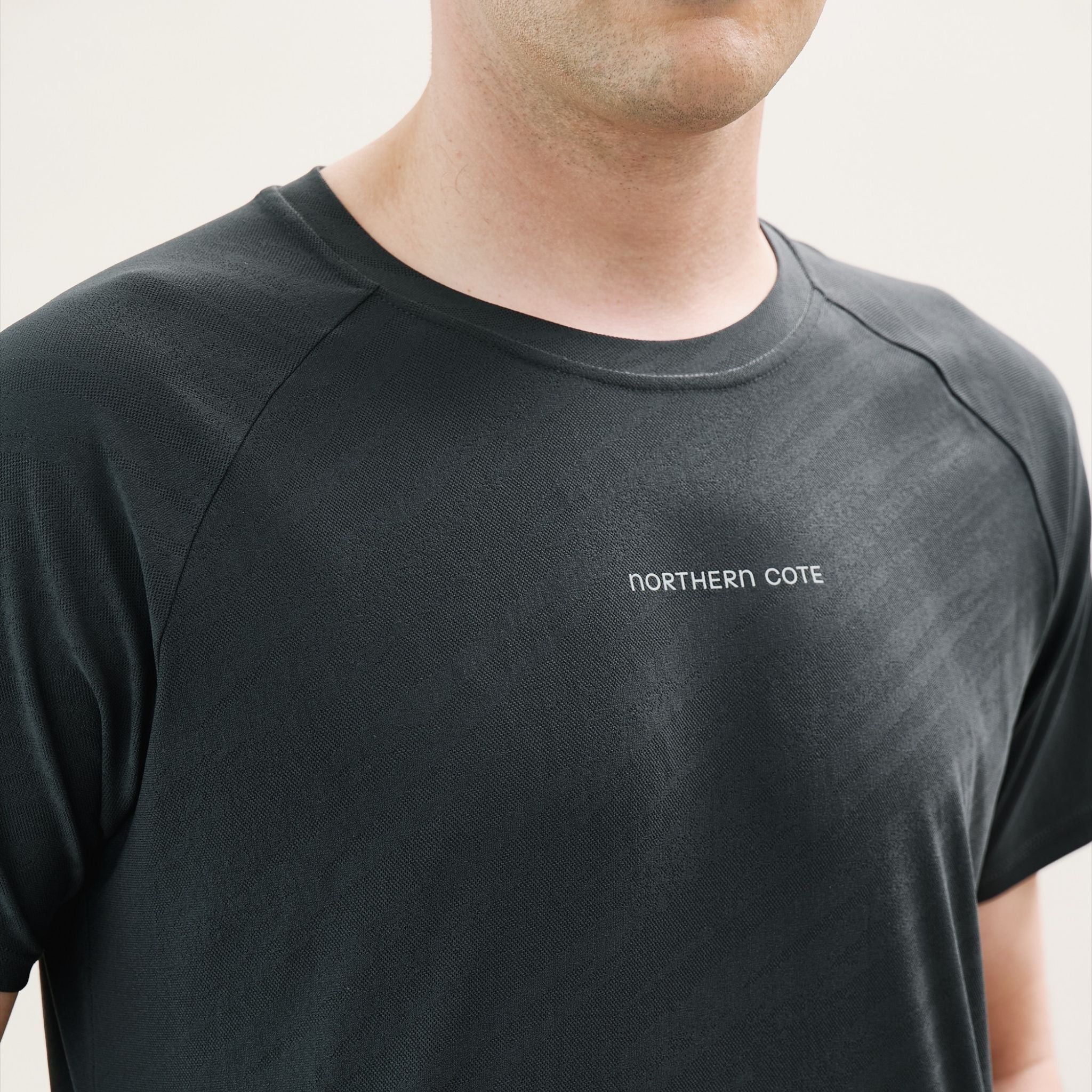 Black t-shirt with logo worn by a person on a white background
