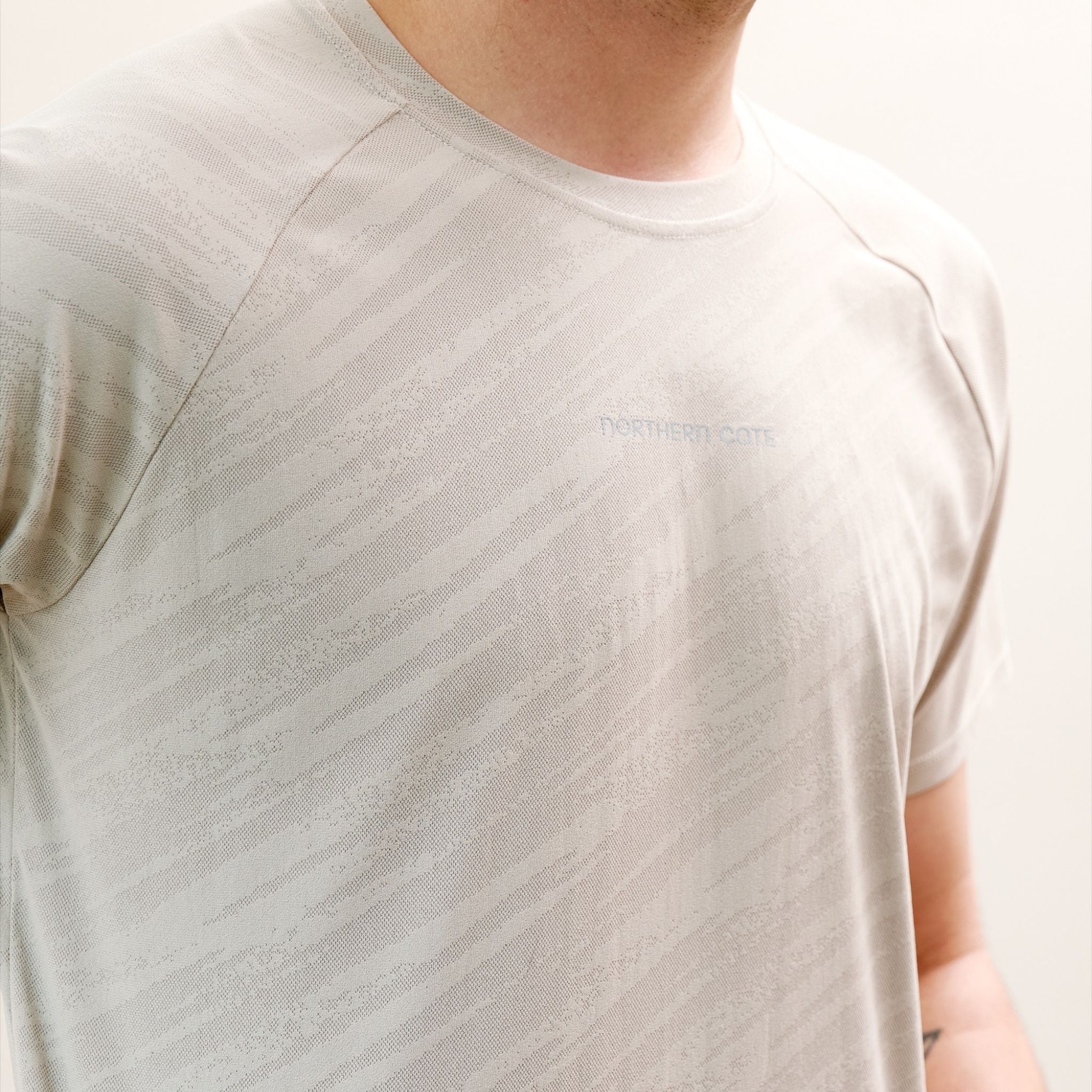 Close-up of a person wearing a textured beige t-shirt.