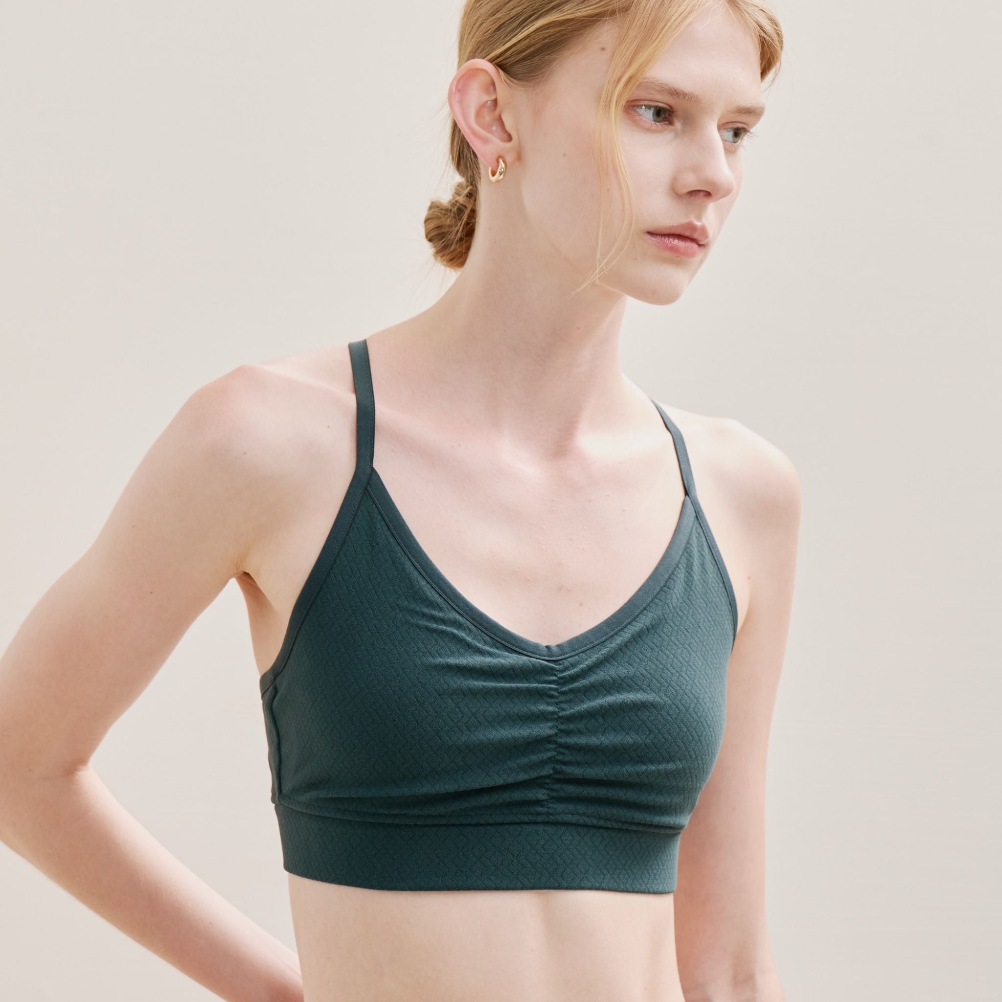 Woman wearing a dark green sports bra against a plain background