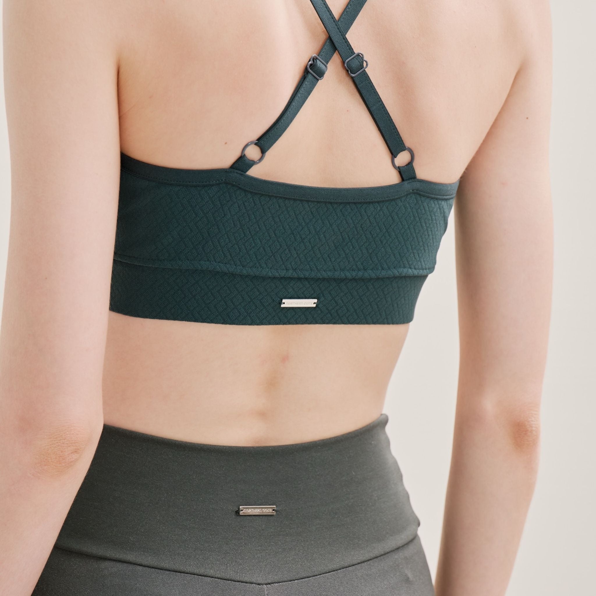 Green sports bra worn by a person on a neutral background