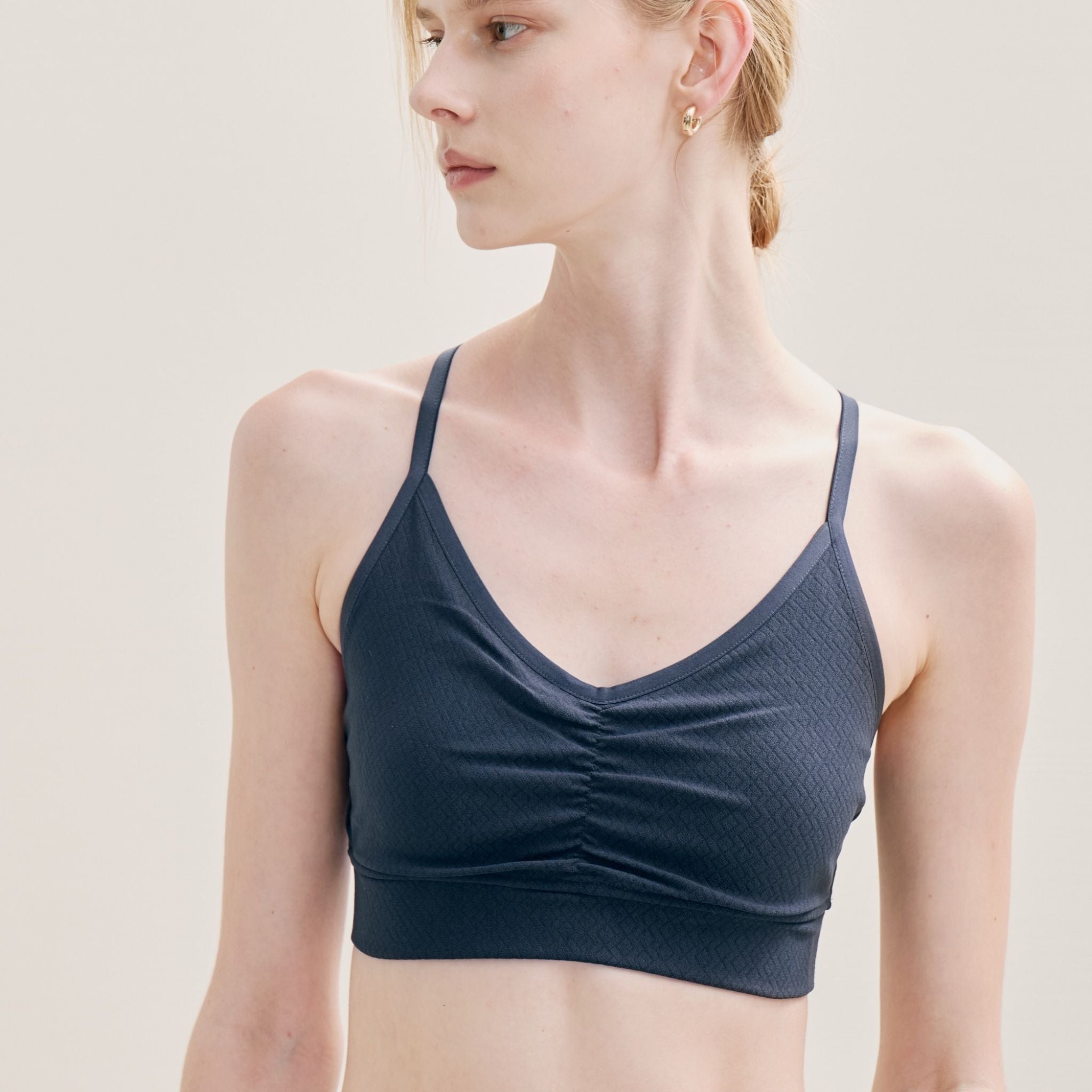 Woman wearing a dark blue sports bra against a plain background