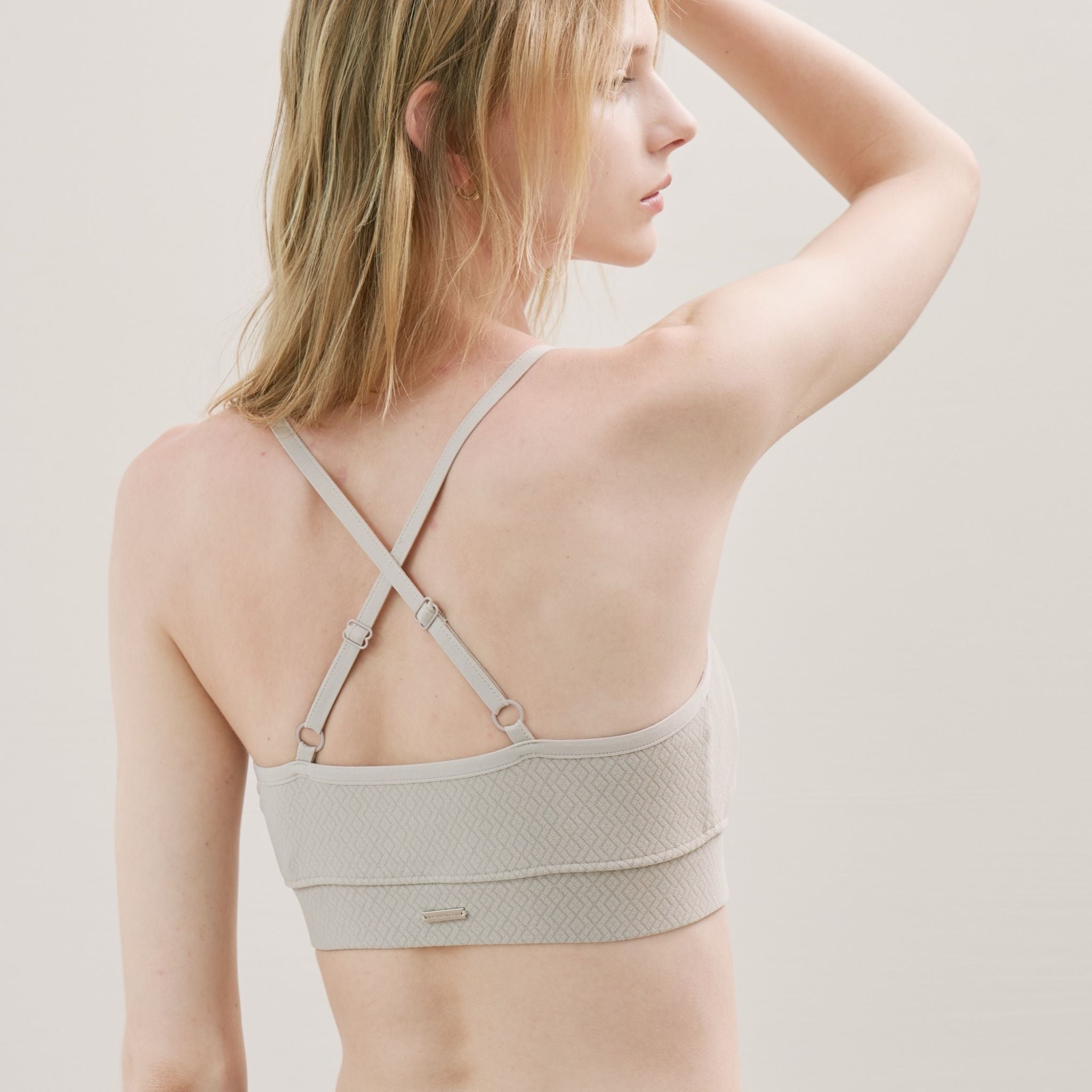 Woman wearing a light gray bralette with a textured pattern.