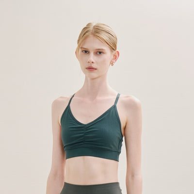 Woman wearing a green sports bra against a plain background