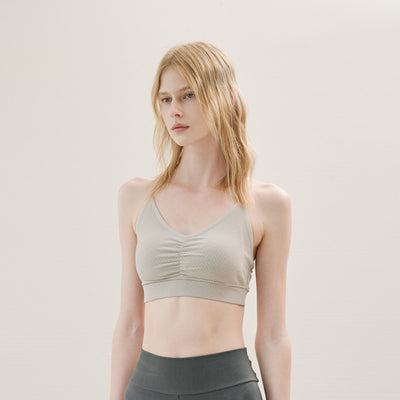 Woman wearing a beige sports bra against a plain background